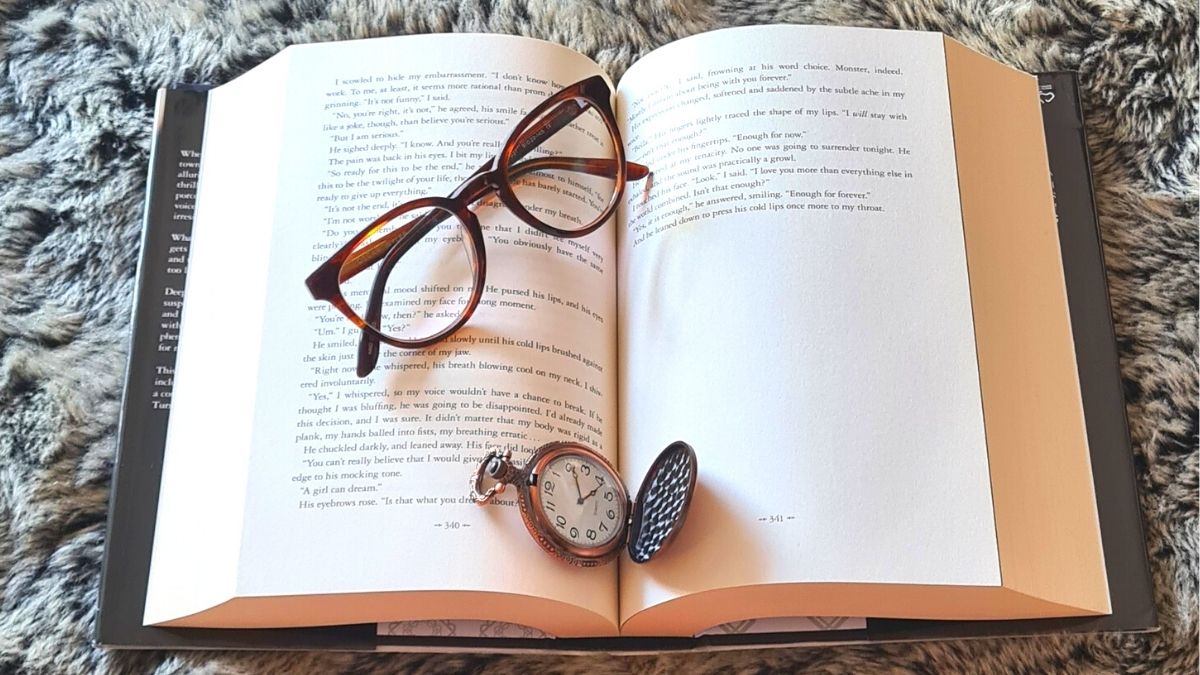 Book with reading glasses and a pocket watch on a soft fur rug