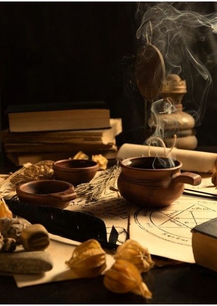 Hot drink on table with magical trinkets and stack of books in background
