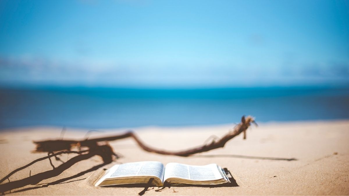 Book on the sand with blurred sea background