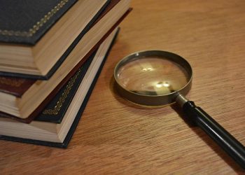 Stack of books and a magnifying glass - mystery